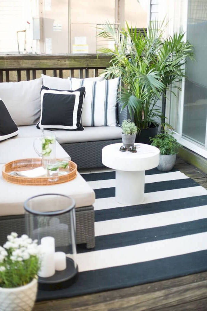 potted plants, next to a corner sofa, with throw pillows, backyard garden ideas, black and white striped rug