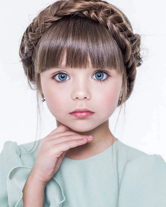 large blue eyes, braided brown hair with bangs, green top, white background, little girl hairstyles