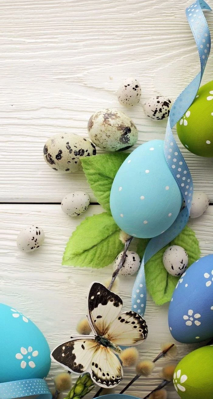 wooden background, green and blue eggs, butterfly and leaves, shaving cream easter eggs
