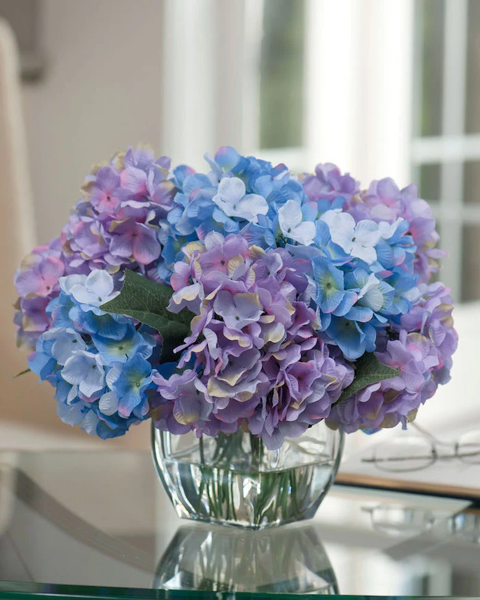 purple and blue flowers, small flower bouquet, flower arrangements, small square glass vase, on a glass table
