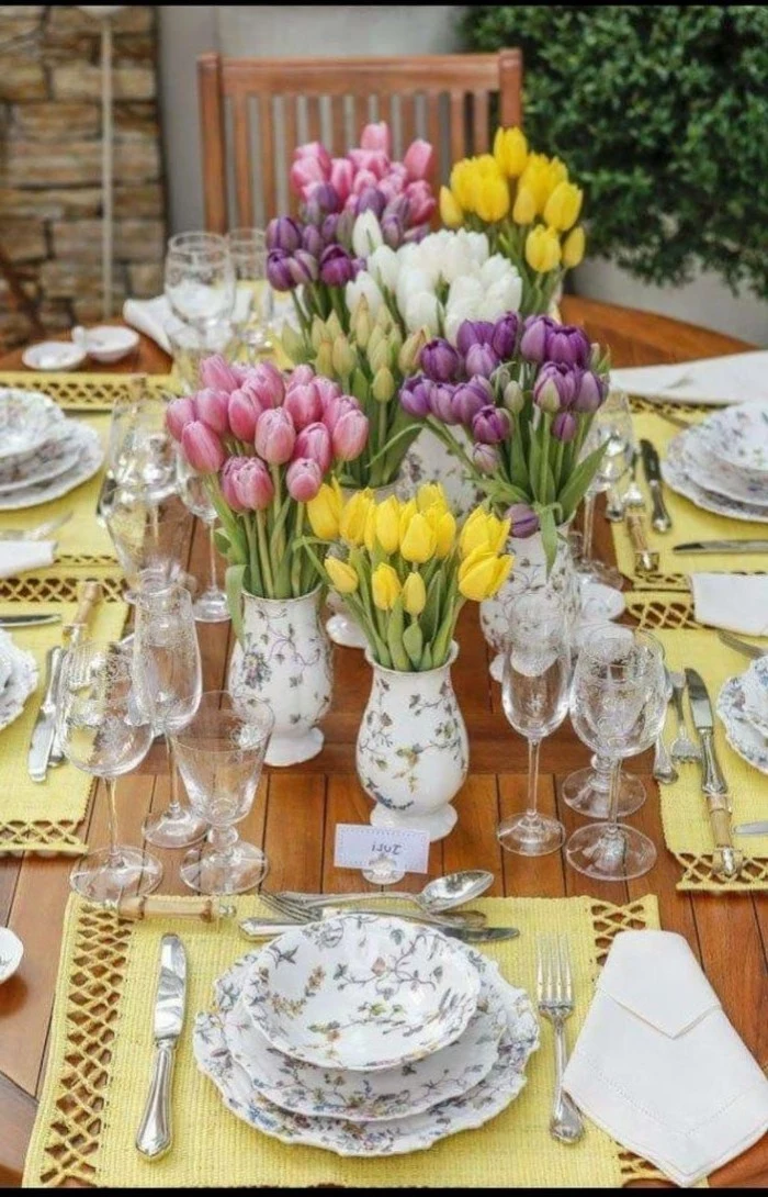 vases full of tilips bouquets, colourful plate settings, simple table decorations, tall wine glasses