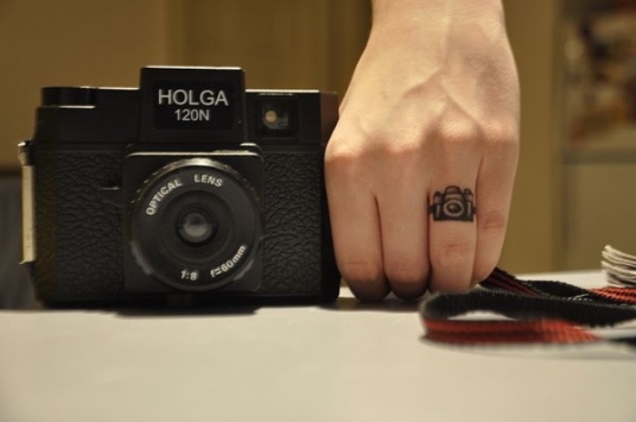 woman holding a vintage camera, small camera finger tattoo, small tattoos for women