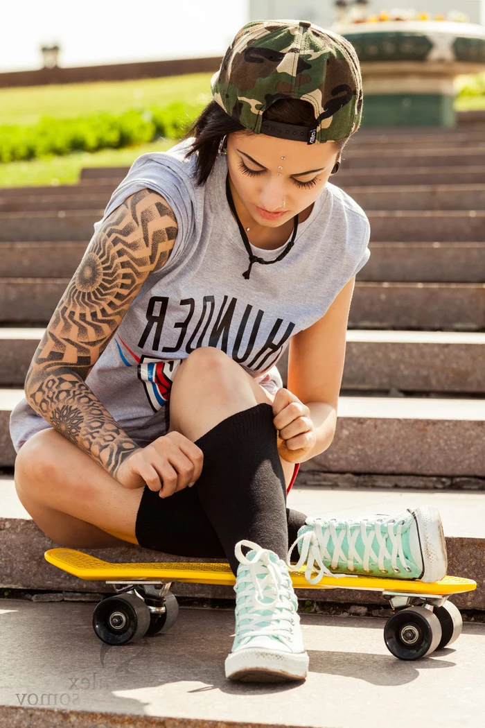 geometric tattoo sleeve, turquoise sneakers, camouflage cap, skateboard girl