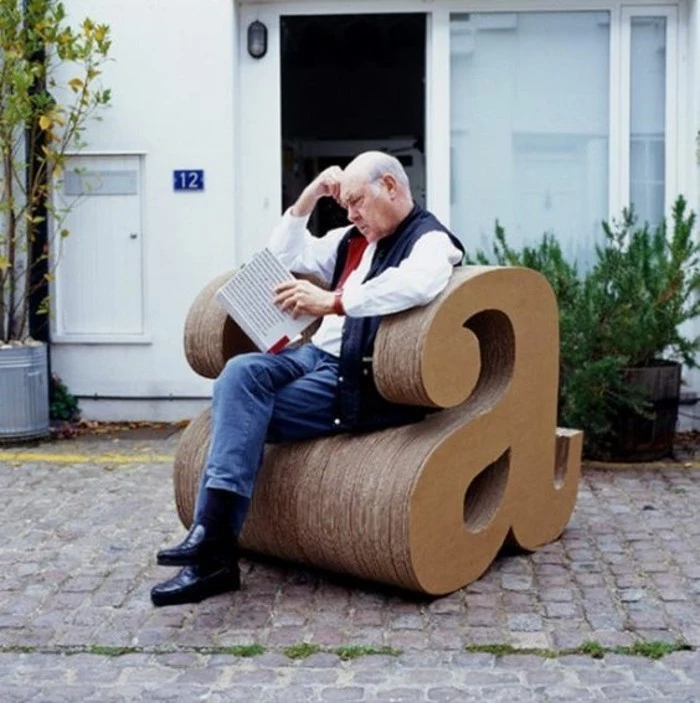 man sitting, on a cardboard armchair, in the shape of the letter a, how to make cardboard
