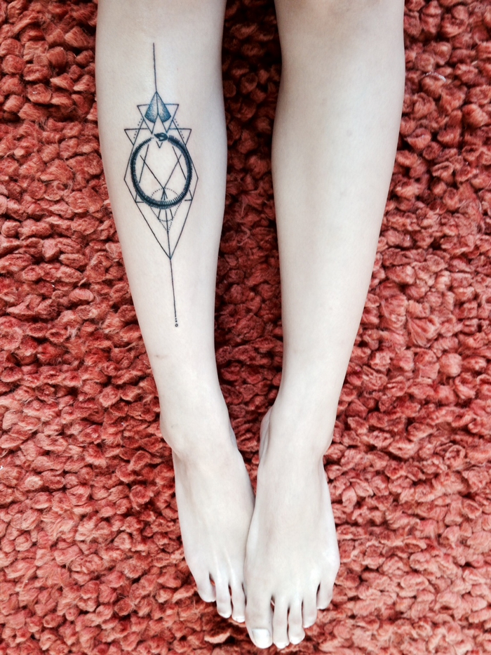 orange background, sacred geometry tattoo, a set of feet, tattoo on the leg, with circle and triangles