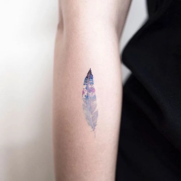 colourful feather forearm tattoo, cool small tattoos, person wearing a black shirt, on a white background