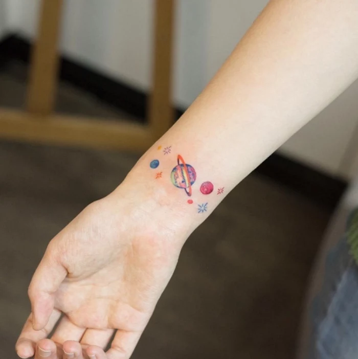 colourful stars and planets wrist tattoo, cool small tattoos, blurred background