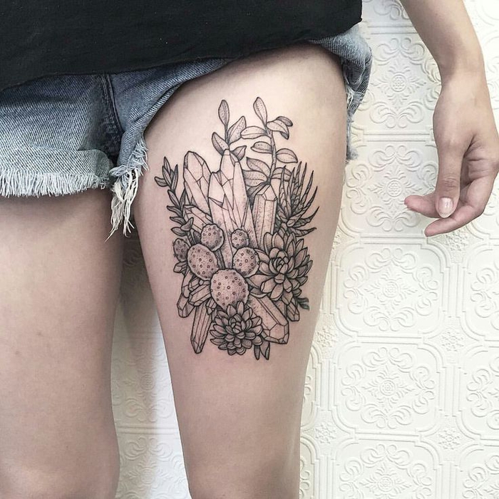 large thigh tattoo, sacred tattoo, flowers and crystals drawing, white background, black shirt and jeans
