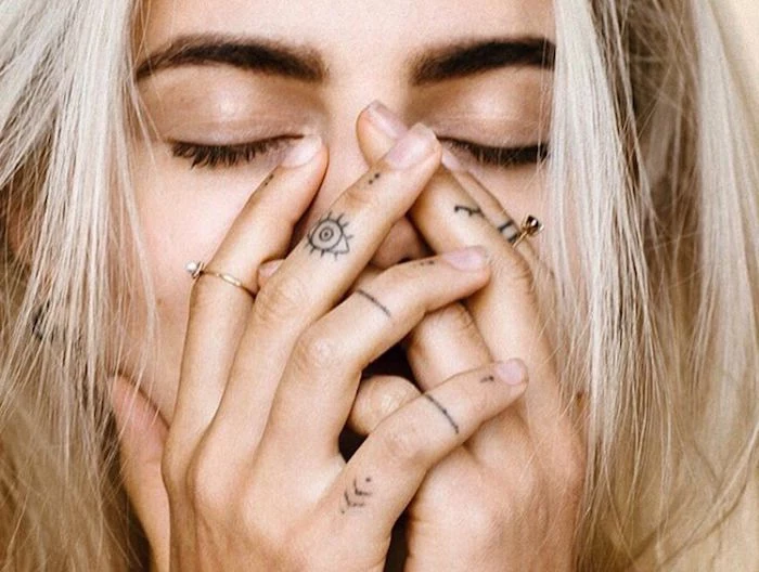 woman covering her face, with her hands, lines dots and eyes finger tattoos, finger tattoos for men, golden rings