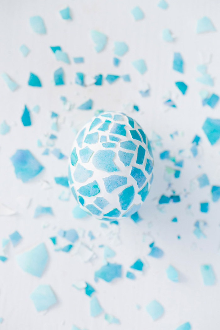 how to dye eggs with food coloring, white egg, blue egg shells on top, spread around, on a white countertop