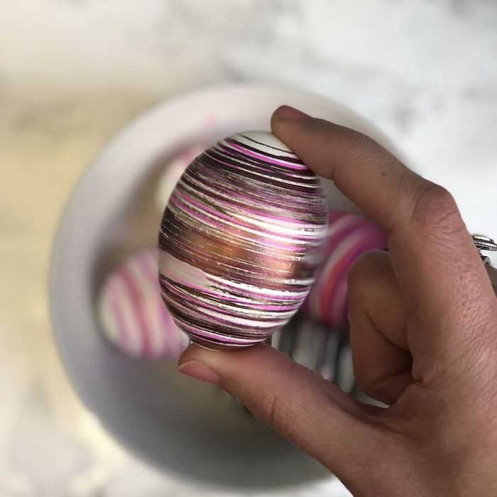 natural egg dye, colourful egg, with gold and rose gold, pink and silver lines, around it, female hand holding it