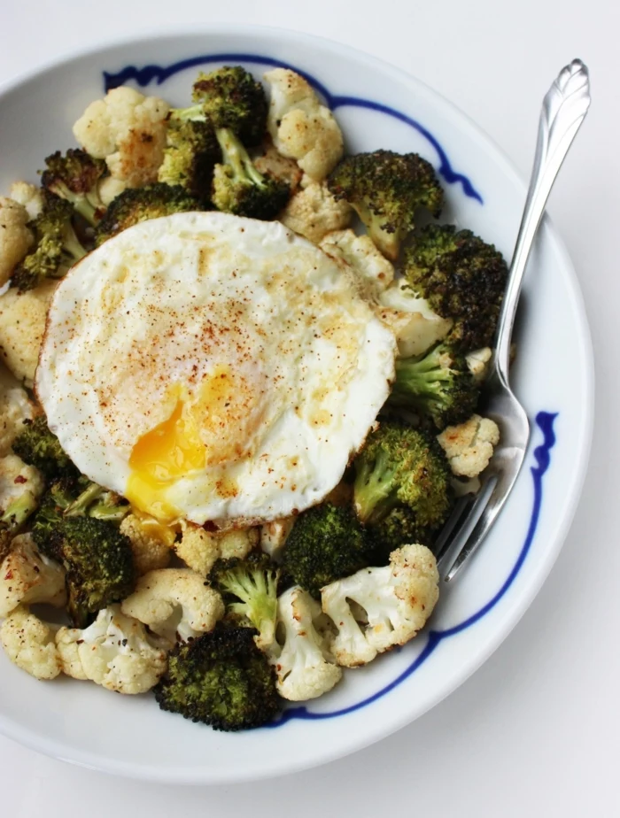 broccoli and cauliflower salad, with an egg on top, diets for women, in a blue and white bowl