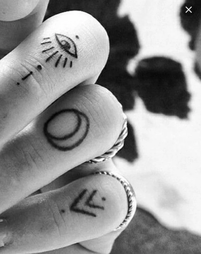 crescent moon arrows and dots, finger tattoos for men, silver rings, blurred black and white background