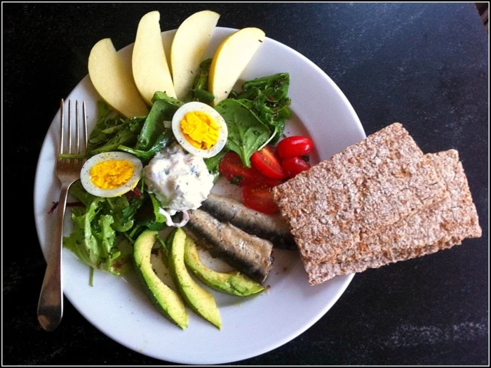 diets for women, white plate, full of green salad, fish and vegetables, boiled egg, apple slices
