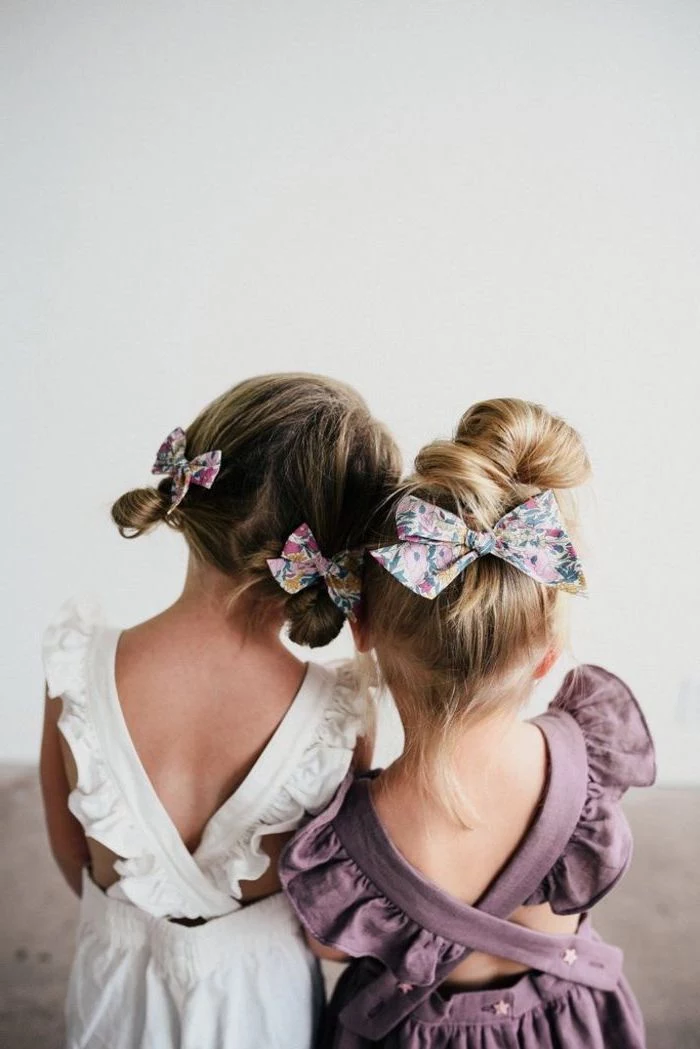 little girl hairstyles, floral bows, messy buns, made on blonde and brown hair, white and purple dresses