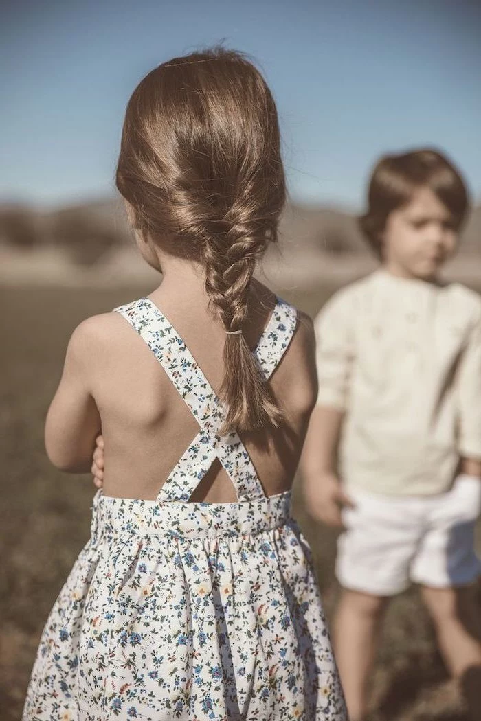 floral dress, little boy in the background, brown hair in a low braid, short hairstyles for girls