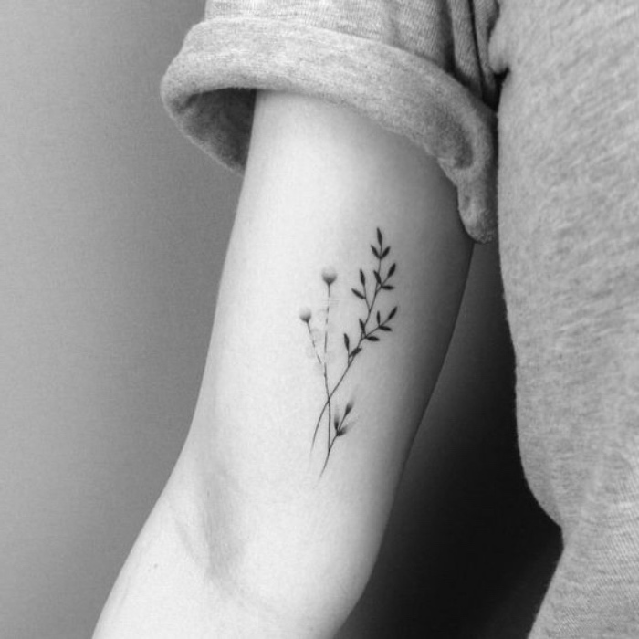 small tattoos with meaning, flowers tattoo inside the arm, person wearing a grey t shirt