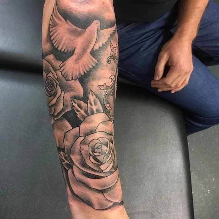 flying bird and roses, forearm tattoo, shoulder tattoos for men, black leather sofa, black shirt and jeans