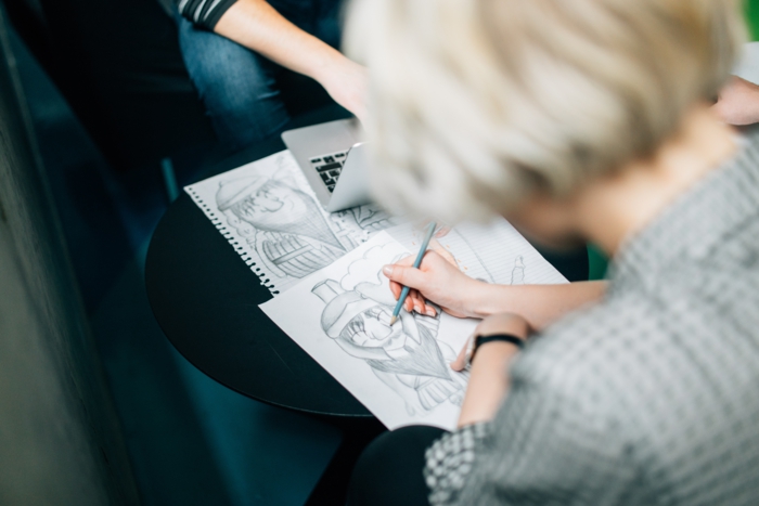 girl sitting and drawing, how to draw a girl face, sketchbook on a black table