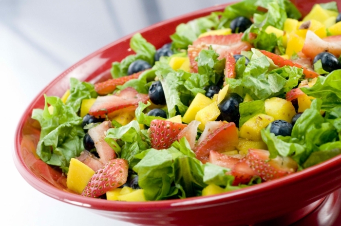 red salad bowl, full of green salad, strawberries and pineapple, fruit salad, healthy diet foods