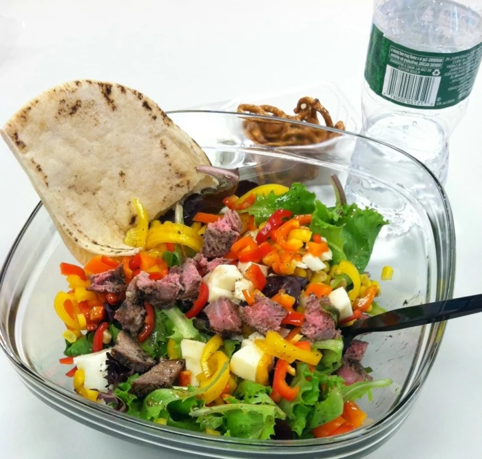 glass salad bowl, full of green salad, peppers and eggs, chopped red meat, healthy diet foods