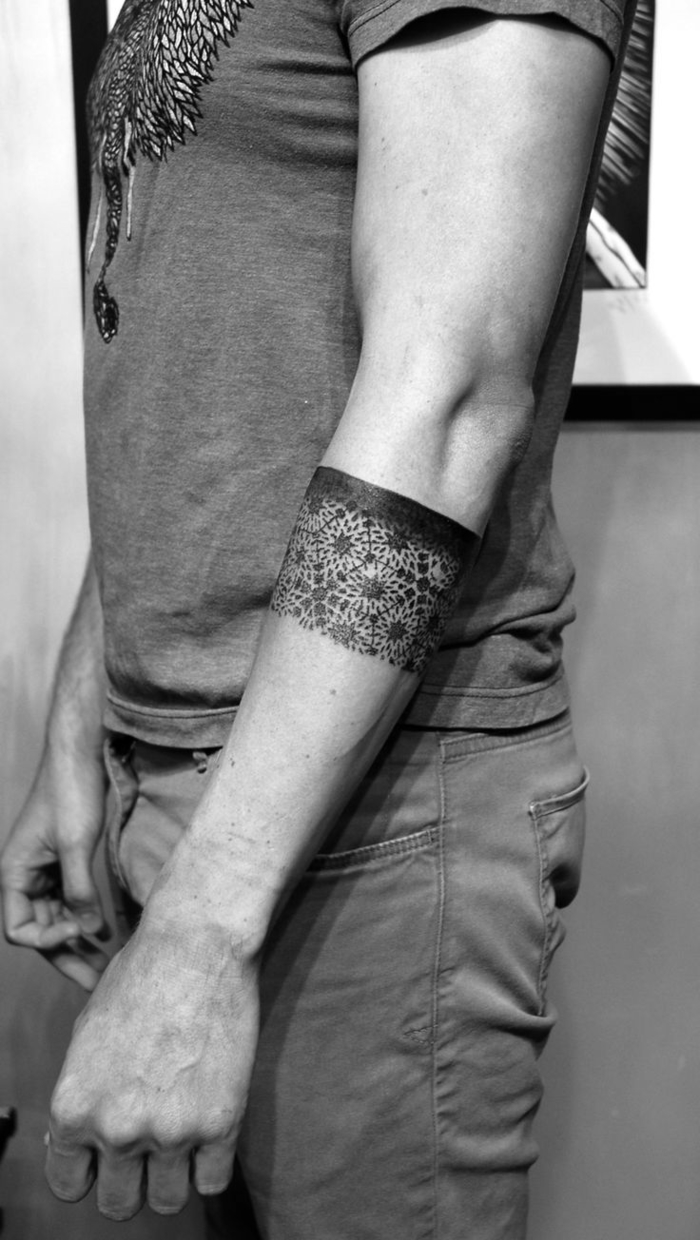 geometrical tattoo, circling the forearm, man standing in front of a wall, geometric animal tattoos