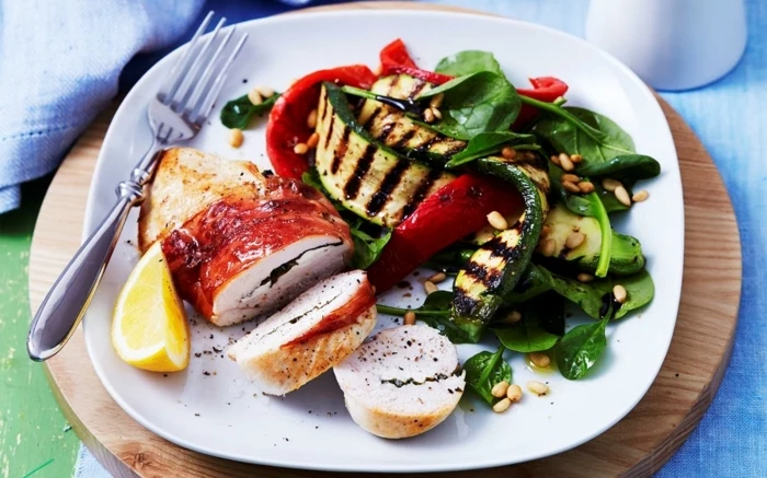 chicken fillet, grilled vegetables, basil and lemon slice on the side, best diet for women, in a white plate