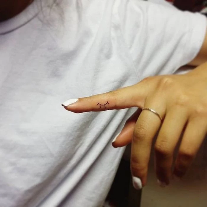 half a sun finger tattoo, small bestfriend tattoos, woman with white nail polish wearing a white shirt