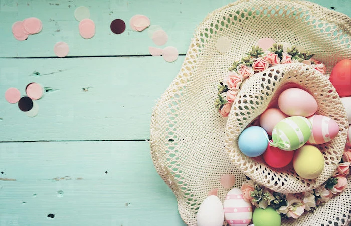 colourful dyed eggs, inside a hat, with flowers on the side, dying easter eggs with food coloring, turquoise backgorund