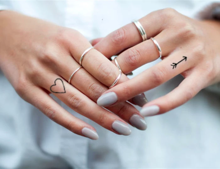 heart and arrow, ring finger tattoos, small finger tattoos, grey nail polish, silver stackable rings