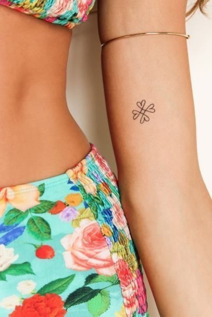 woman wearing a floral swimsuit, small flower heart forearm tattoo, small tattoos, golden bracelet