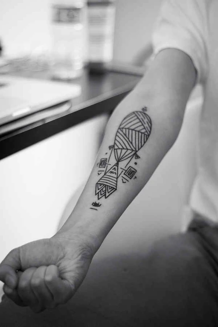 geometric animal tattoos, geometrical hot air balloon, on the forearm, man sitting down