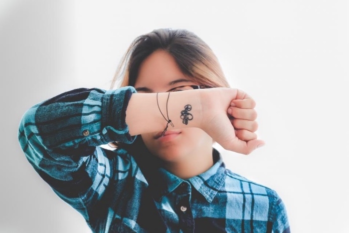 inscription wrist tattoo, woman wearing a blue plaid shirt, with brown hair, small bestfriend tattoos