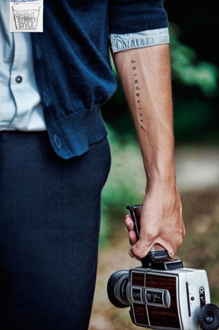 joie de vivre forearm tattoo, small bestfirend tattoos, man carrying a vintage camera, wearing a blue cardigan
