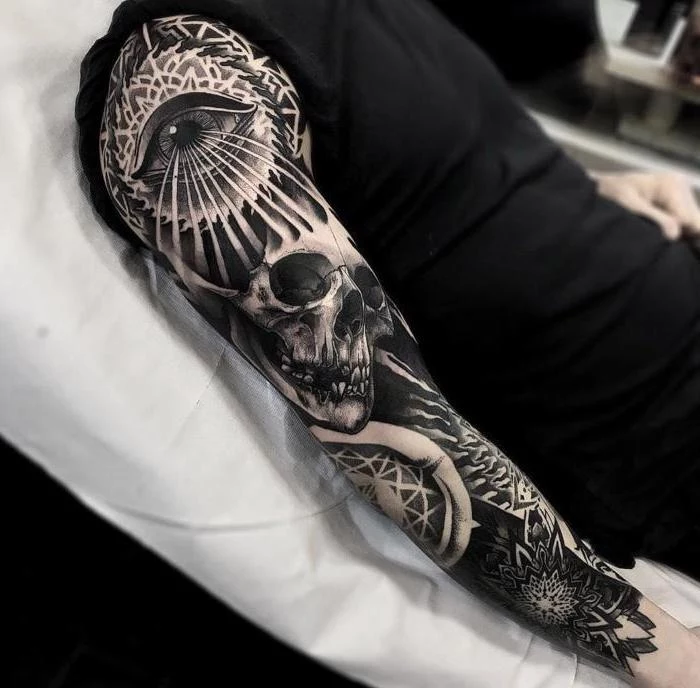 black and white, arm sleeve tattoo, back tattoos for men, man dressed in all black, lying on a table