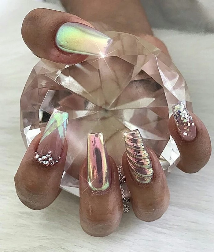 hand holding a large diamond, monochromatic nail polish, with small rhinestones, nude nail designs