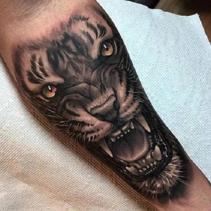 large lion head, forearm tattoo, wrist tattoos for men, hand lying on a white paper sheet