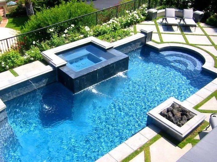 large pool, with a small hot tub, garden patio ideas, cement tiles, two grey lounge chairs, planted flowers