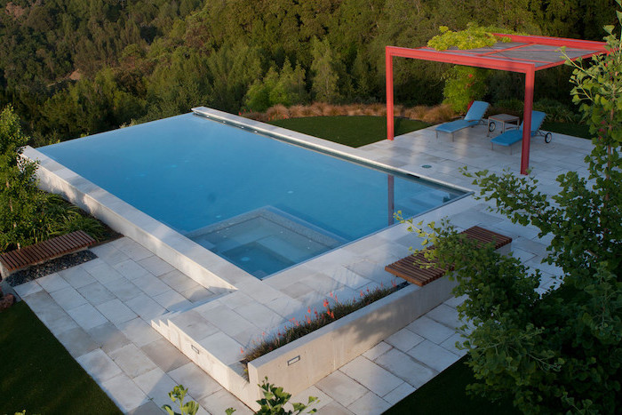 small pool, two blue lounge chairs, tiled floor, garden patio ideas, planted flowers and trees