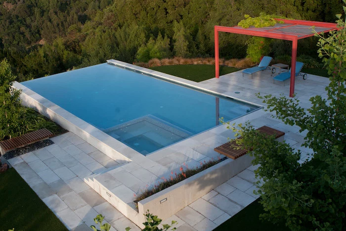 small pool, two blue lounge chairs, tiled floor, garden patio ideas, planted flowers and trees