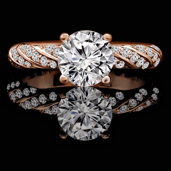 large round diamond, diamond studded rose gold band, teardrop engagement ring, black background
