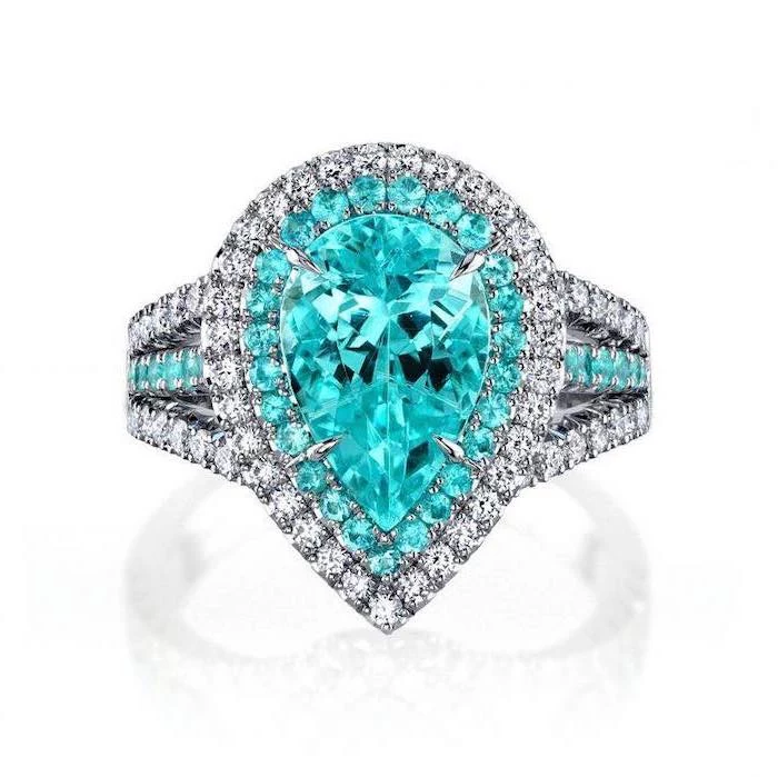 large teardrop emerald stone, diamond studded band, round halo engagement rings, white background