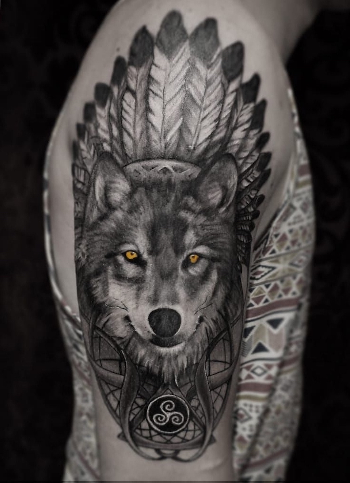large wolf head, feathers on top, shoulder tattoo, forearm tattoos, man wearing a printed top