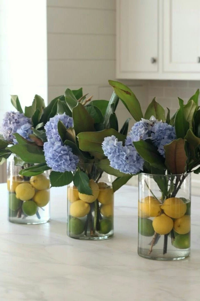 lemons floating in the water, in a round vase, flower arrangement ideas, blue flowers in three vases