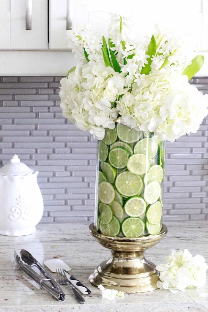 lime slices in a large round vase, white flowers bouquet, on a granite countertop, flower arrangement ideas