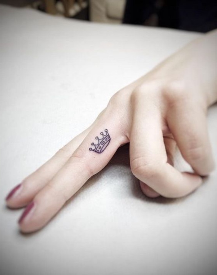 small crown finger tattoo, hand in front of a white background, small tattoo ideas for men