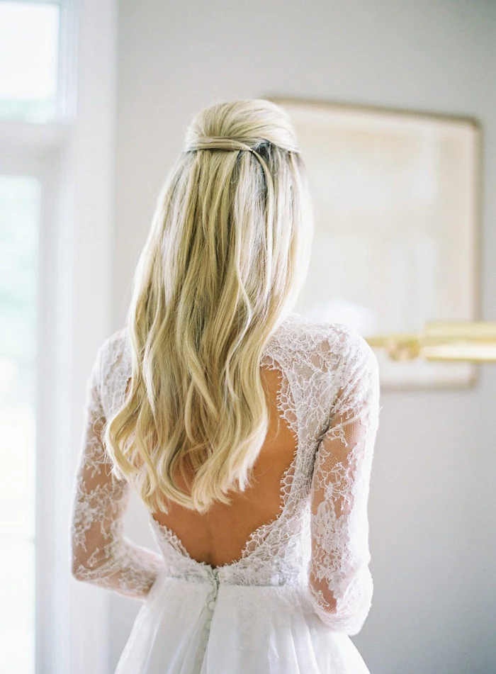 long wavy blonde hair, wedding hairstyle, white dress with lace, blurred background