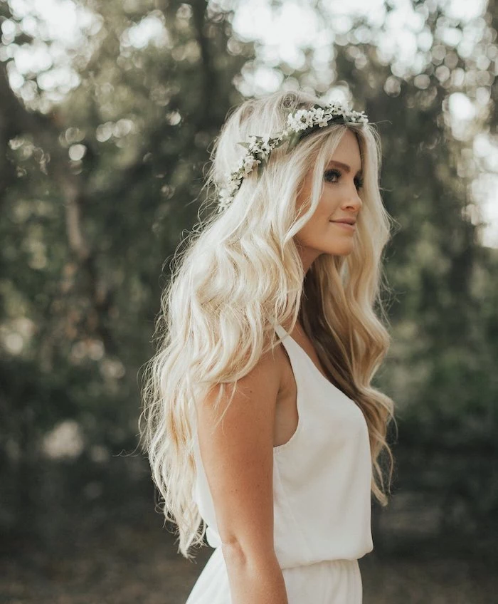 long wavy blonde hair, floral headband, long hair wedding styles, white dress, blurred background