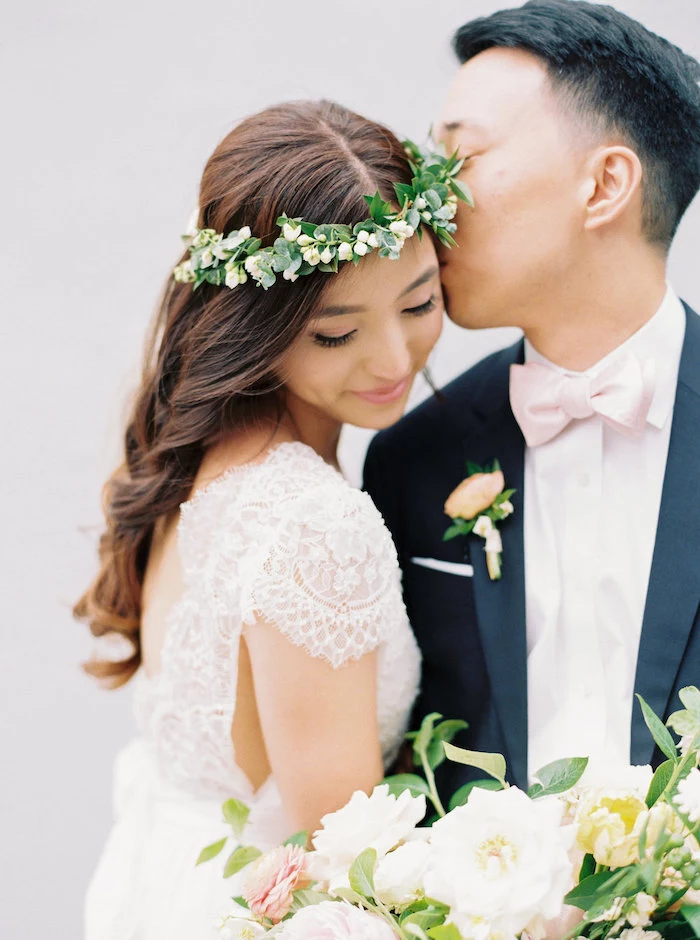 long wavy brown hair, floral headband, long hair wedding styles, man kissing a woman, flower bouquet 