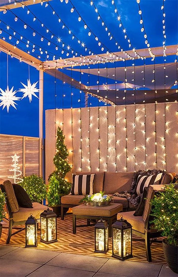 many strings of lights, over garden furniture, with throw pillows, small space gardening, potted plants